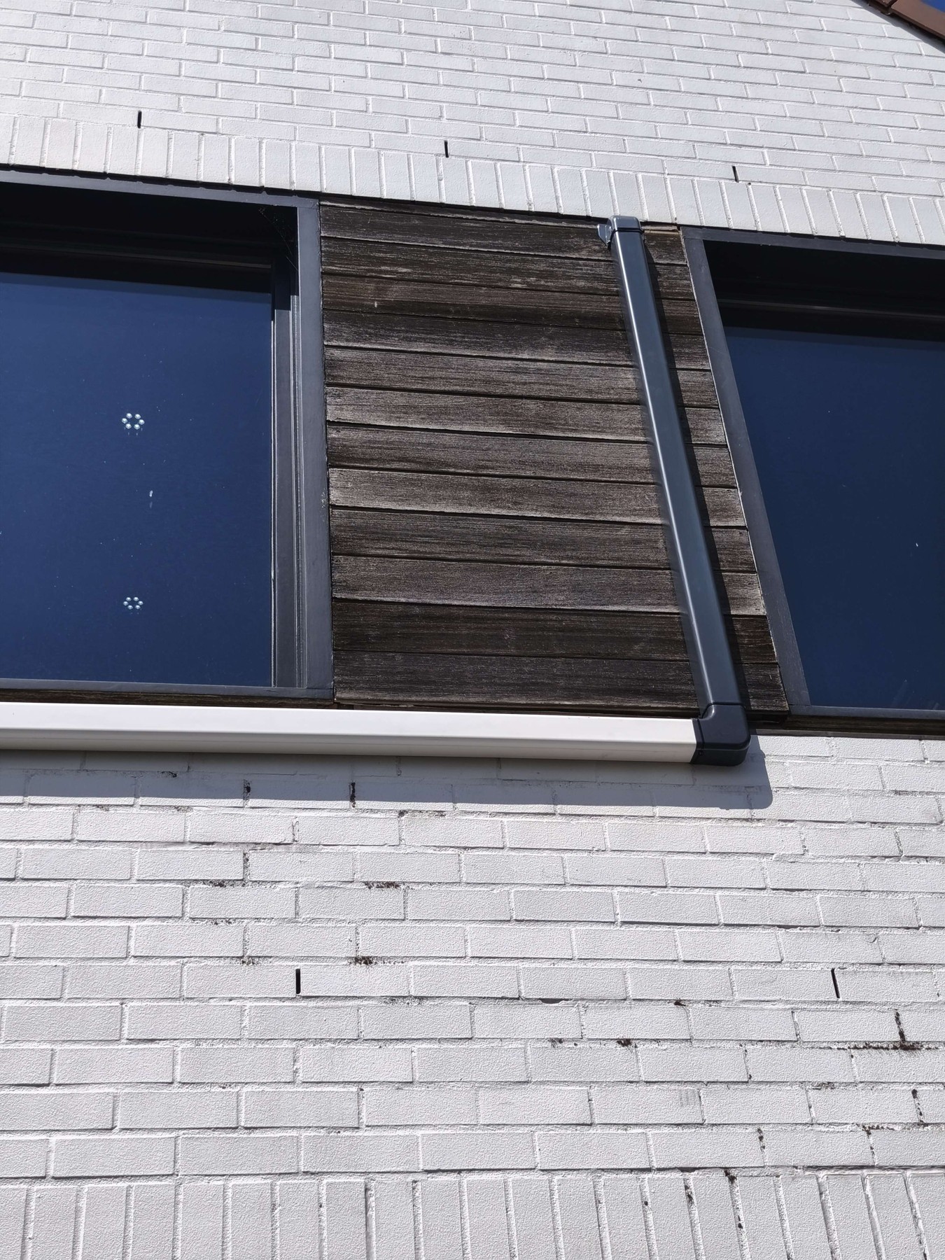 Zwarte kabelgoot langs de donkere gevelbekleding